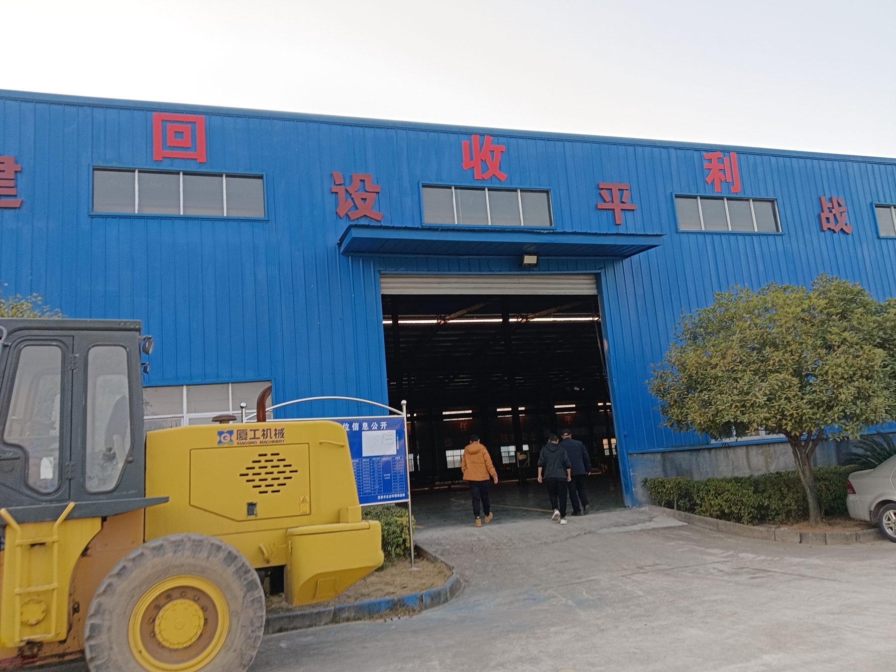 Blue recycling plant building with a wheel loader outside